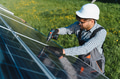 Technician installing solar panels in green field using screwdriver - PhotoDune Item for Sale