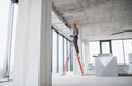 Construction worker installing ventilation system on a ladder in building under construction - PhotoDune Item for Sale
