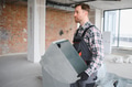 Construction worker carrying ventilation pipes in building under construction - PhotoDune Item for Sale