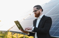 Engineer using laptop analyzing solar panels in sustainable energy plant - PhotoDune Item for Sale