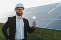 Engineer showing light bulb near solar panels in sustainable energy concept - PhotoDune Item for Sale