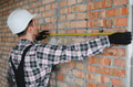 Construction worker measuring brick wall with tape measure - PhotoDune Item for Sale