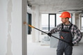 Construction worker painting walls with roller in building renovation - PhotoDune Item for Sale