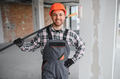 Smiling builder holding paint roller during renovation works - PhotoDune Item for Sale