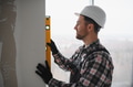 Construction worker checking wall straightness with spirit level - PhotoDune Item for Sale