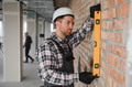 Construction worker checking brick wall straightness with spirit level - PhotoDune Item for Sale