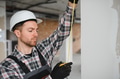 Construction worker measuring wall with tape measure in building under construction - PhotoDune Item for Sale