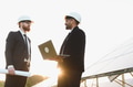 Engineers discussing using laptop near solar panels at sunset - PhotoDune Item for Sale