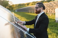 Businessman working with laptop in solar panel farm for renewable energy - PhotoDune Item for Sale