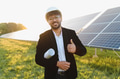 Engineer showing thumbs up while inspecting solar panels in green field - PhotoDune Item for Sale