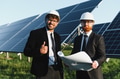 Engineers inspecting plans for solar panel installation in field - PhotoDune Item for Sale