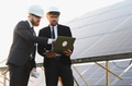 Engineers using laptop analyzing solar panel farm for renewable energy - PhotoDune Item for Sale