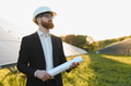 Investor inspecting solar panel farm with blueprint at sunset - PhotoDune Item for Sale