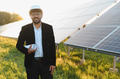 Arab engineer holding blueprint in solar panel farm at sunset - PhotoDune Item for Sale