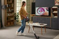 Young Woman Vacuuming Living Room While Watching Television - PhotoDune Item for Sale