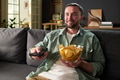 Man Relaxing on Sofa Watching Television and Eating Chips - PhotoDune Item for Sale