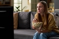 Young Adult Woman Watching Television While Eating Popcorn Indoors - PhotoDune Item for Sale