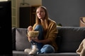 Young Adult Woman Sitting on Sofa Watching Television and Eating Popcorn - PhotoDune Item for Sale