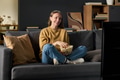 Young Woman Sitting on Sofa Watching Television and Eating Popcorn - PhotoDune Item for Sale
