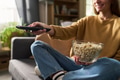 Young Woman Sitting on Sofa Watching Television and Eating Popcorn - PhotoDune Item for Sale