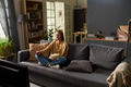 Young Adult Woman Sitting Cross Legged on Sofa Watching Comedy Show - PhotoDune Item for Sale
