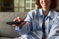 Young Adult Woman Smiling While Holding Television Remote Control - PhotoDune Item for Sale