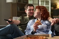 Young Adult Couple Relaxing on Sofa Eating Pizza and Watching Television - PhotoDune Item for Sale