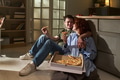 Young Man and Woman Sitting on Floor Eating Pizza Together Indoors - PhotoDune Item for Sale