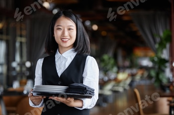 Young Asian woman as classic server holding tray in restaurant