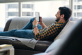 Man Reading Ebook With Ereader Lying On Couch - PhotoDune Item for Sale