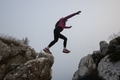 silhouette of a fitness woman trail runner jumping over a cliff and running to a rocky mountain top - PhotoDune Item for Sale
