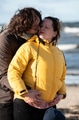 A couple stands embraced on a sandy beach on a chilly autumn day, the serene ocean stretching behind - PhotoDune Item for Sale
