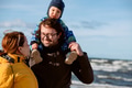 A happy family strolls along a chilly autumn beach, with their young son joyfully running ahead - PhotoDune Item for Sale