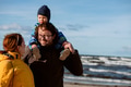 A happy family strolls along a chilly autumn beach, with their young son joyfully running ahead - PhotoDune Item for Sale