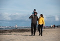 A happy family strolls along a chilly autumn beach, with their young son joyfully running ahead - PhotoDune Item for Sale