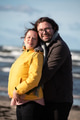 A couple stands embraced on a sandy beach on a chilly autumn day, the serene ocean stretching behind - PhotoDune Item for Sale