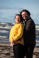 A couple stands embraced on a sandy beach on a chilly autumn day, the serene ocean stretching behind - PhotoDune Item for Sale