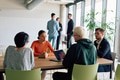 A diverse team of business professionals engaged in a discussion around a conference table in an - PhotoDune Item for Sale