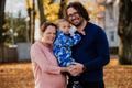 On a sunny autumn day in the park, a mother and father lovingly embrace their young son, sharing - PhotoDune Item for Sale
