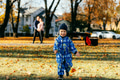 A joyful little boy in his winter coat and hat plays happily in the park, surrounded by the love and - PhotoDune Item for Sale