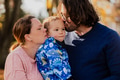 On a sunny autumn day in the park, a mother and father lovingly embrace their young son, sharing - PhotoDune Item for Sale