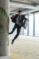 A businessman ecstatically jumping in a modern office, holding a briefcase in his hands, celebrating - PhotoDune Item for Sale