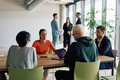 A diverse team of business professionals engaged in a discussion around a conference table in an - PhotoDune Item for Sale