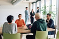 A diverse team of business professionals engaged in a discussion around a conference table in an - PhotoDune Item for Sale