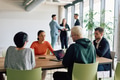 A diverse team of business professionals engaged in a discussion around a conference table in an - PhotoDune Item for Sale