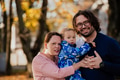 On a sunny autumn day in the park, a mother and father lovingly embrace their young son, sharing - PhotoDune Item for Sale