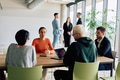A diverse team of business professionals engaged in a discussion around a conference table in an - PhotoDune Item for Sale