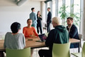 A diverse team of business professionals engaged in a discussion around a conference table in an - PhotoDune Item for Sale