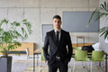 A close up portrait of a company director in a black suit, standing confidently in a modern office - PhotoDune Item for Sale