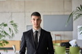 A close up portrait of a company director in a black suit, standing confidently in a modern office - PhotoDune Item for Sale